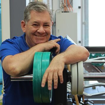 lächelnder Mitarbeiter beim Gesundheitssport mit Gewichten