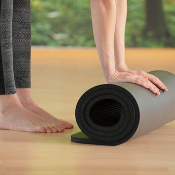 Teilnehmerin rollt schwarze Yogamatte  zusammen